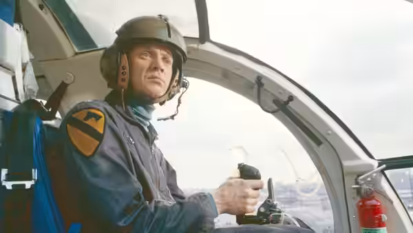 Murphy (Roy Scheider) sits in the helicopter cockpit, holding a radio