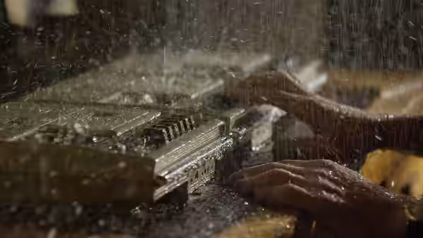 Hands play a piano as water pours across the keys