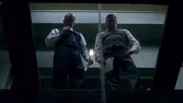 Two men stand above a trapdoor in an execution chamber