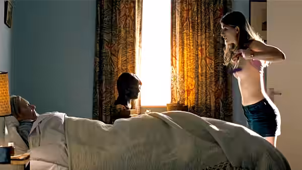 Jessie (Jodie Whittaker) stands beside Maurice (Peter O'Toole), who lies in bed