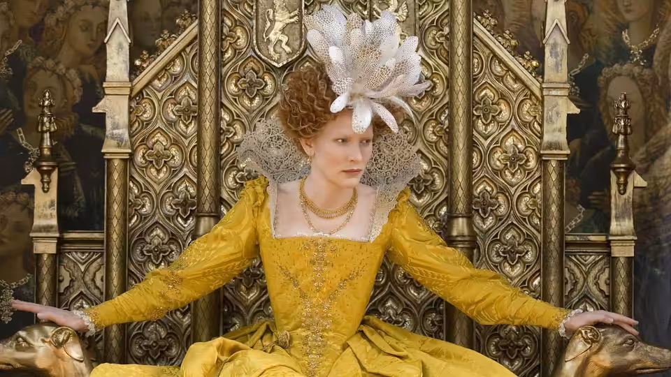 Elizabeth I (Cate Blanchett) sits on an ornate throne in a yellow gown