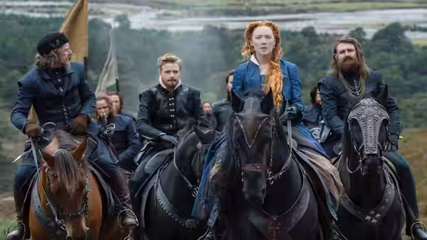 Mary Stuart (Saoirse Ronan) rides with armed companions across the Scottish countryside