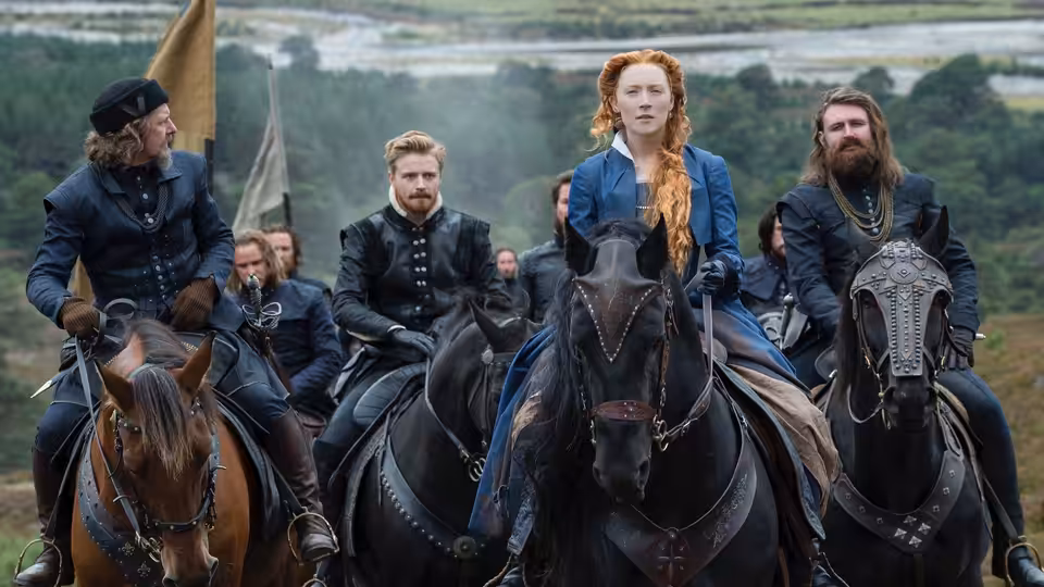Mary Stuart (Saoirse Ronan) rides with armed companions across the Scottish countryside