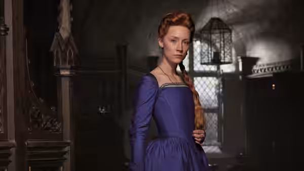 Mary Stuart (Saoirse Ronan) stands in a purple gown inside a palace