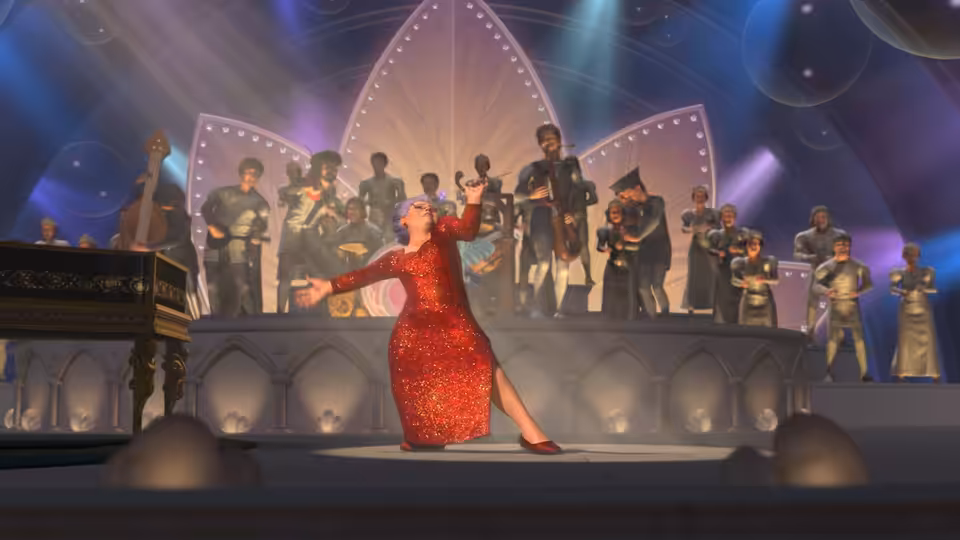 Fairy Godmother performs in a red gown before a crowd on a brightly lit stage