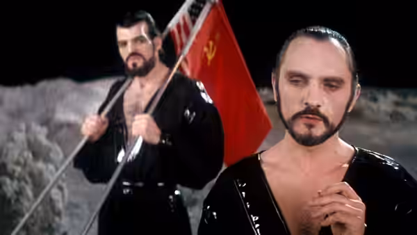General Zod (Terence Stamp) stands before Non (Jack O'Halloran), who holds a flag