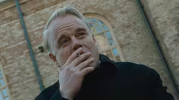 Father Flynn (Philip Seymour Hoffman) smokes outside the brick school building