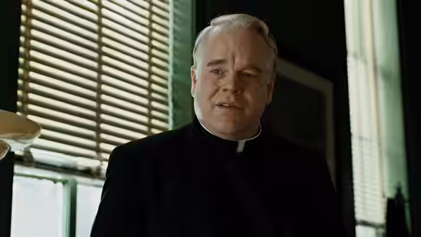 Father Flynn (Philip Seymour Hoffman) stands beside a window in his office