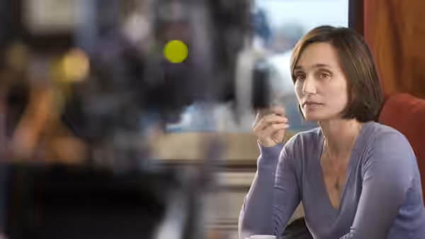 Juliette (Kristin Scott Thomas) holds a cigarette while seated at a café