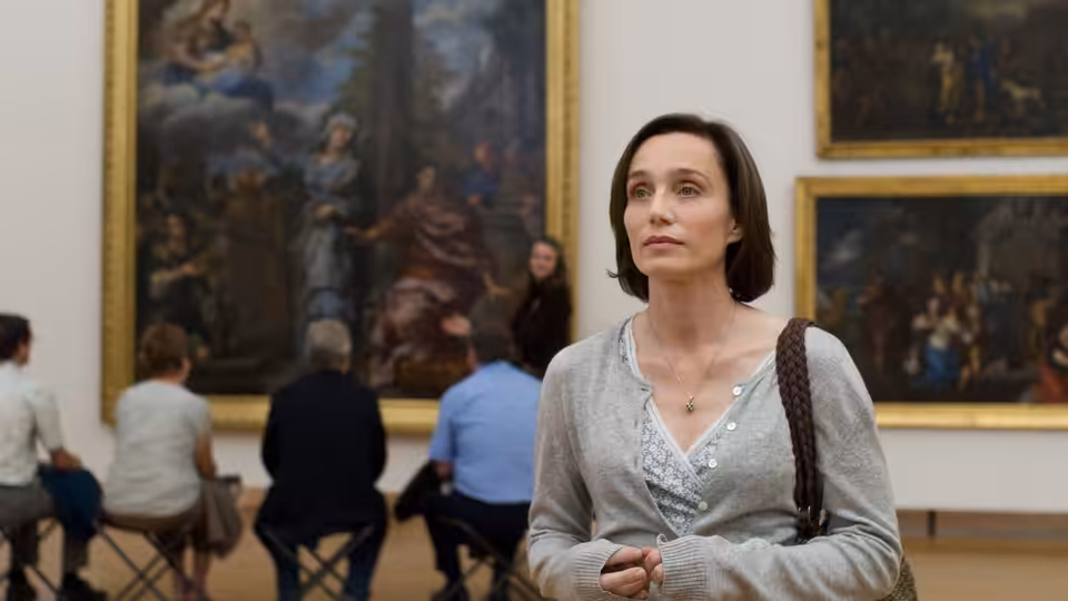 Juliette (Kristin Scott Thomas) stands before large paintings in an art gallery