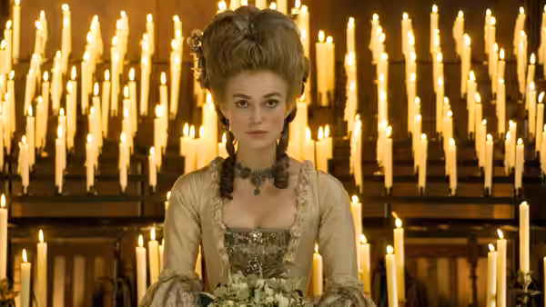 Georgiana Cavendish (Keira Knightley) holds a bouquet before rows of glowing candles