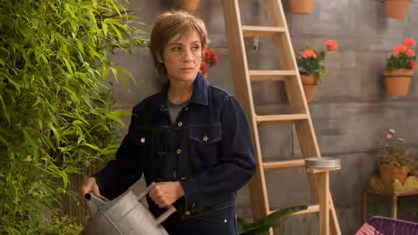 Judit García (Blanca Portillo) holds a watering can among potted plants