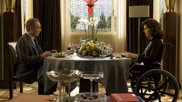 Ernesto Martel (José Luis Gómez) and Lena (Penélope Cruz) sit across a dining table