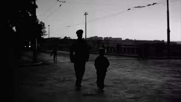 Man and boy walk together along a wide empty street at dusk