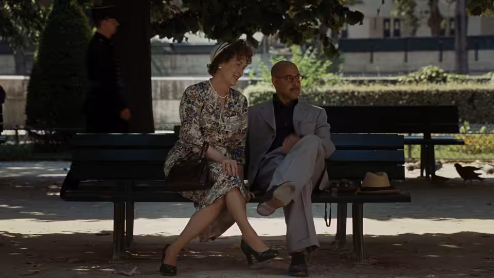 Julia Child (Meryl Streep) sits with Paul Child (Stanley Tucci) on a park bench