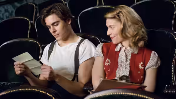 Richard Samuels (Zac Efron) reads a paper beside Sonja Jones (Claire Danes) in a theater
