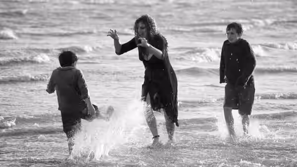 Saraghina (Fergie) plays with two boys in the shallow surf