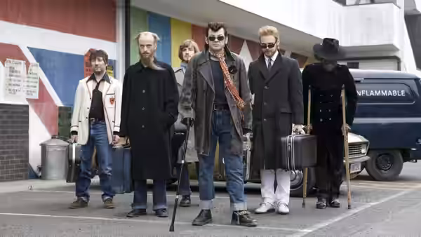 Ian Dury (Andy Serkis) and his bandmates stand outside a van with instruments