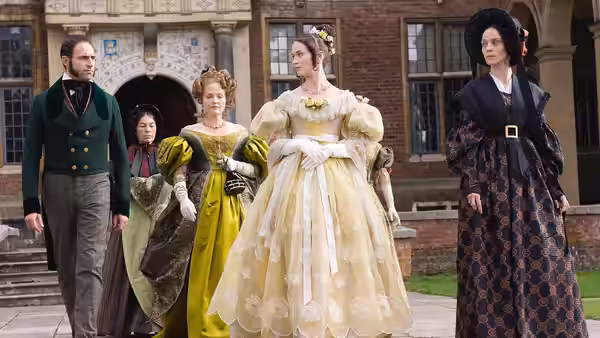 Queen Victoria (Emily Blunt) walks with attendants through a palace courtyard