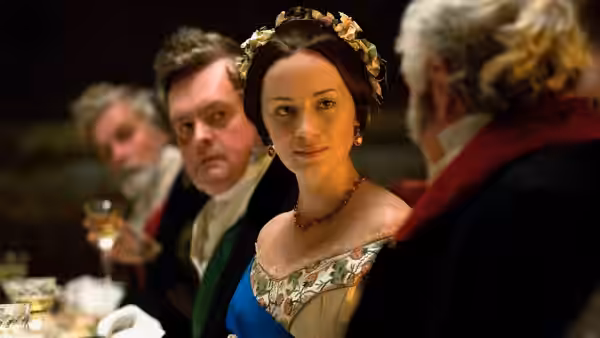 Queen Victoria (Emily Blunt) sits among men at a formal dinner