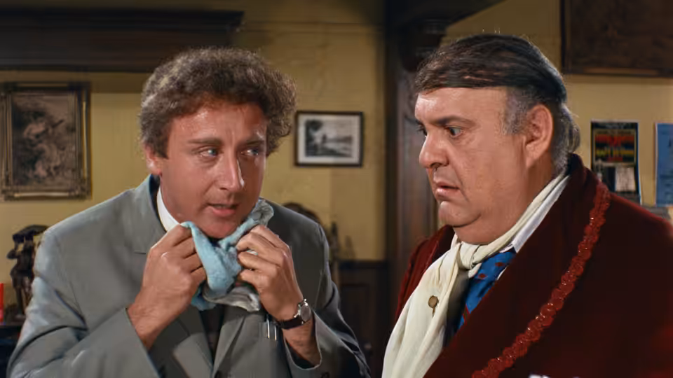 Leo Bloom adjusts his bow tie while Max Bialystock watches him closely