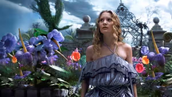 Alice (Mia Wasikowska) stands among oversized flowers in a garden
