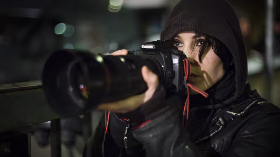 Lisbeth Salander (Noomi Rapace) aims a long-lens camera from beneath her hood