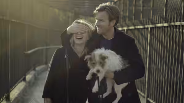 Oliver (Ewan McGregor) covers Anna’s eyes as they walk their dog along a fenced path
