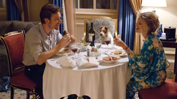 Oliver (Ewan McGregor) and Anna (Mélanie Laurent) share dinner across a table with their dog