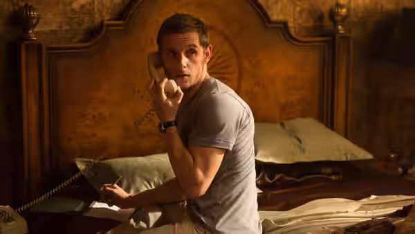Peter Turner (Jamie Bell) sits on a bed, holding a telephone receiver and a book