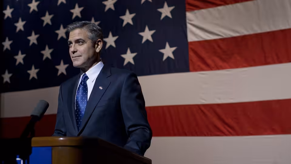 Mike Morris (George Clooney) stands at a lectern before an American flag