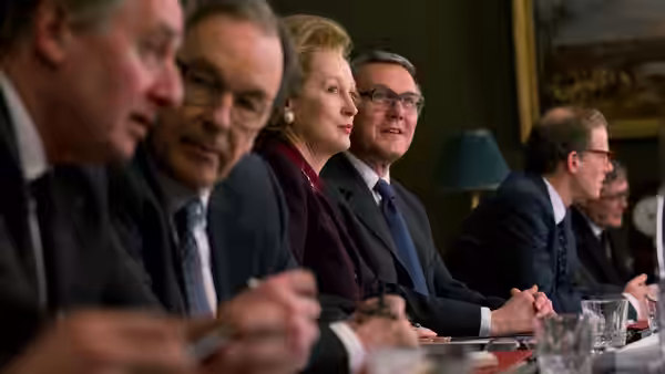 Margaret Thatcher (Meryl Streep) sits among suited officials at a conference table