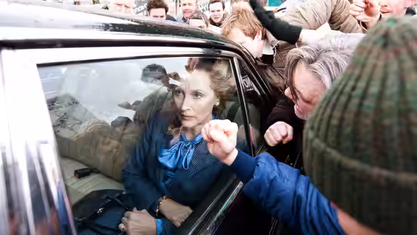 Margaret Thatcher (Meryl Streep) sits in a car surrounded by a crowd pressing at its window