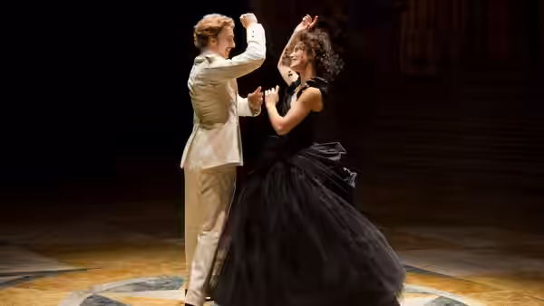 Anna Karenina (Keira Knightley) dances with a man in white on a dark stage
