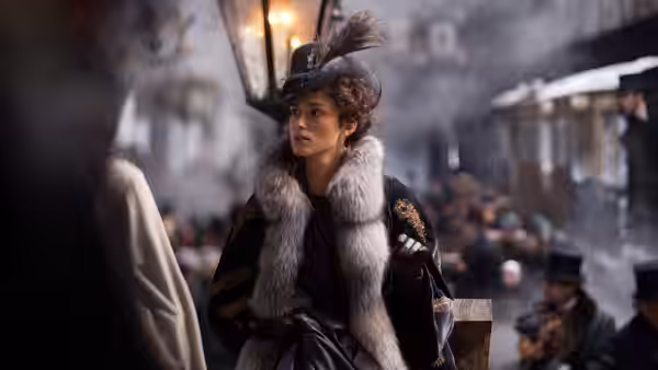 Anna Karenina (Keira Knightley) walks through a crowded street in a feathered hat and fur collar