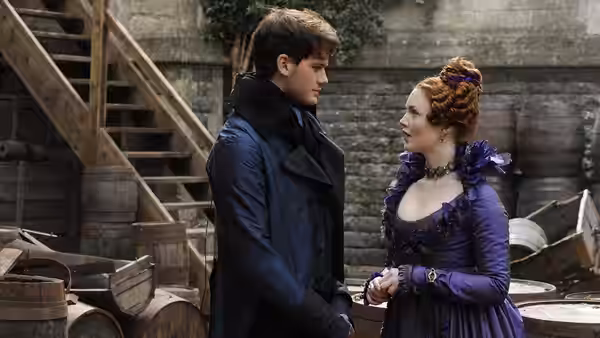Pip (Jeremy Irvine) and Estella (Holliday Grainger) face each other in a stone courtyard