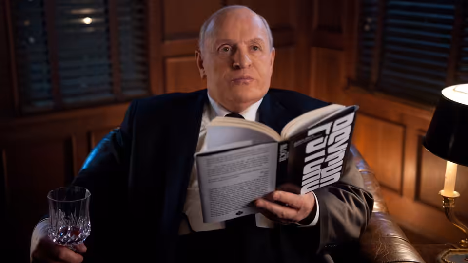 Alfred Hitchcock (Anthony Hopkins) reads a book in a wood-paneled room