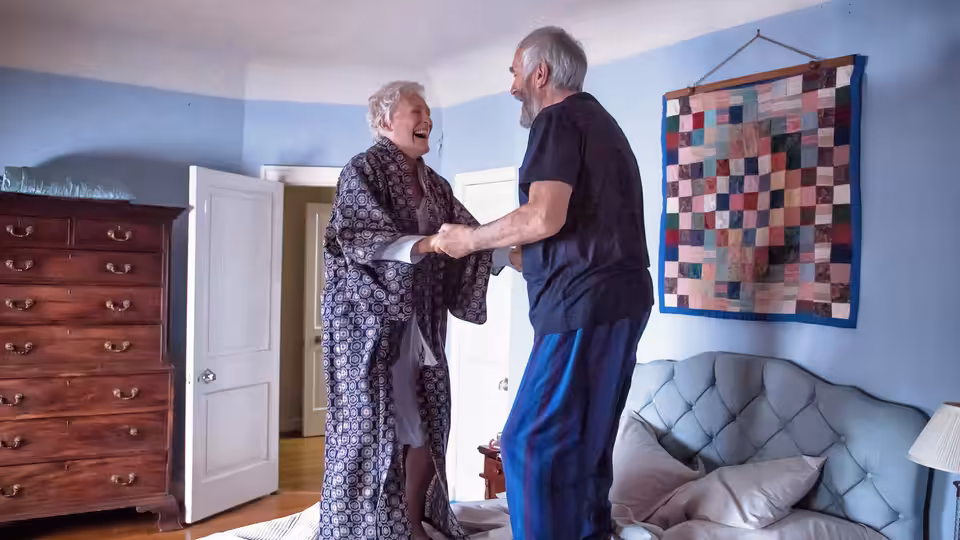 Joan Castleman (Glenn Close) and Joe Castleman (Jonathan Pryce) hold hands in their bedroom