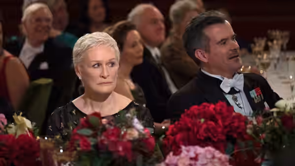 Joan Castleman (Glenn Close) sits beside a tuxedoed man at a banquet