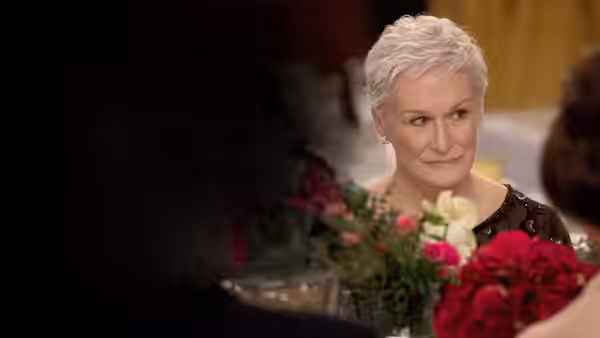 Joan Castleman (Glenn Close) sits at a banquet table among flowers