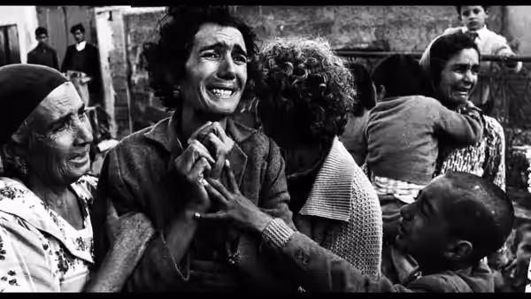 A distressed woman clutches another person's hand as people gather around her
