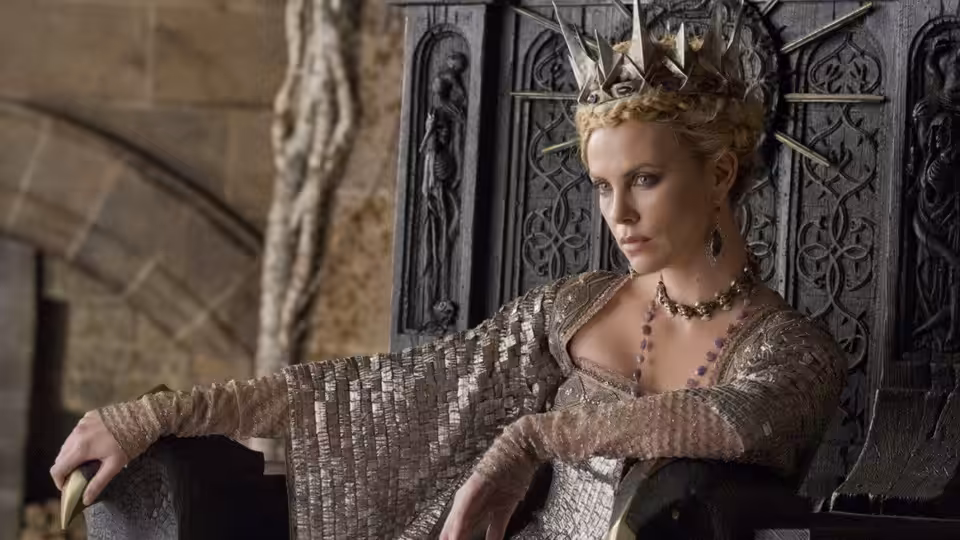 Queen Ravenna (Charlize Theron) sits crowned before an ornate throne