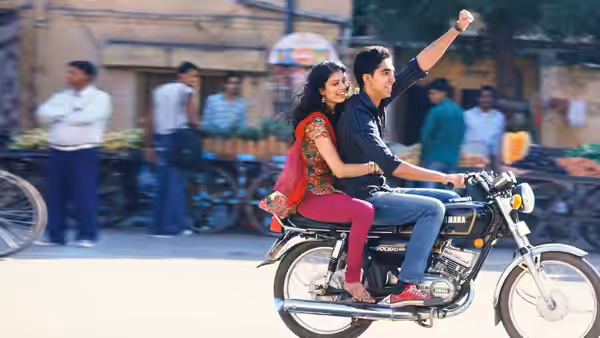 Sonny Kapoor (Dev Patel) rides a motorcycle through the street with Sunaina behind him