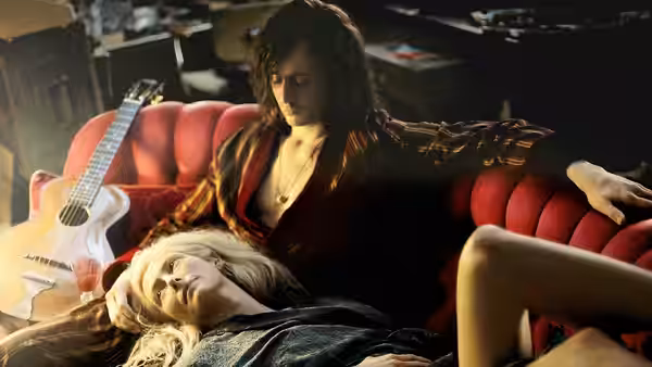 Adam (Tom Hiddleston) reclines on a red couch with Eve (Tilda Swinton) beside him