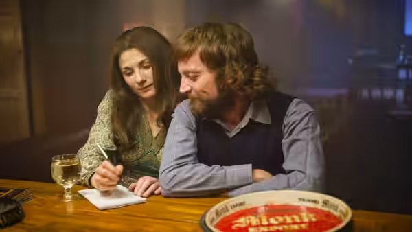 Ruth (Jodie Whittaker) watches Terri Hooley (Richard Dormer) write at a pub table