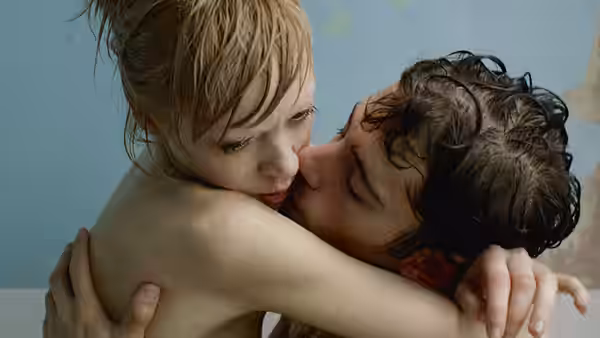 Kelly (Antonia Campbell-Hughes) embraces and kisses Victor (Julian Morris) against a pale wall