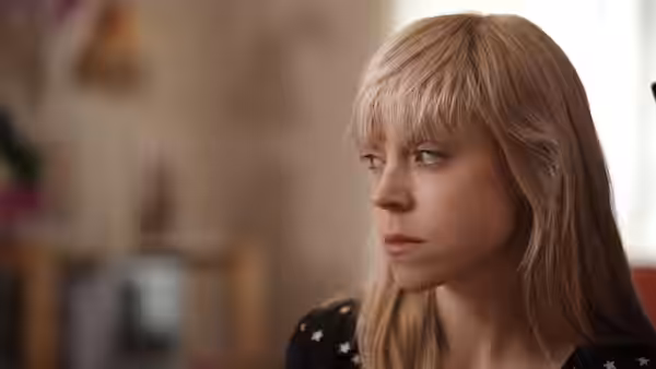 Kelly (Antonia Campbell-Hughes) looks sideways while sitting indoors