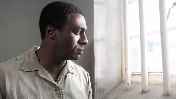 Nelson Mandela (Idris Elba) looks out through barred prison windows