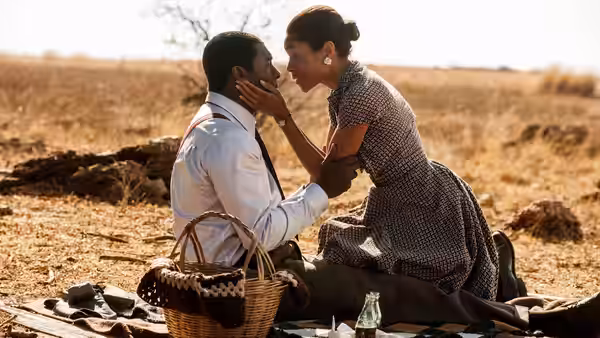 Nelson Mandela (Idris Elba) and Winnie Madikizela (Naomie Harris) sit together in a dry field