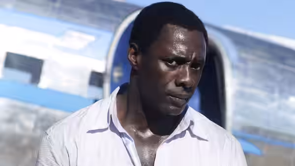 Nelson Mandela (Idris Elba) stands tensely beside a vehicle
